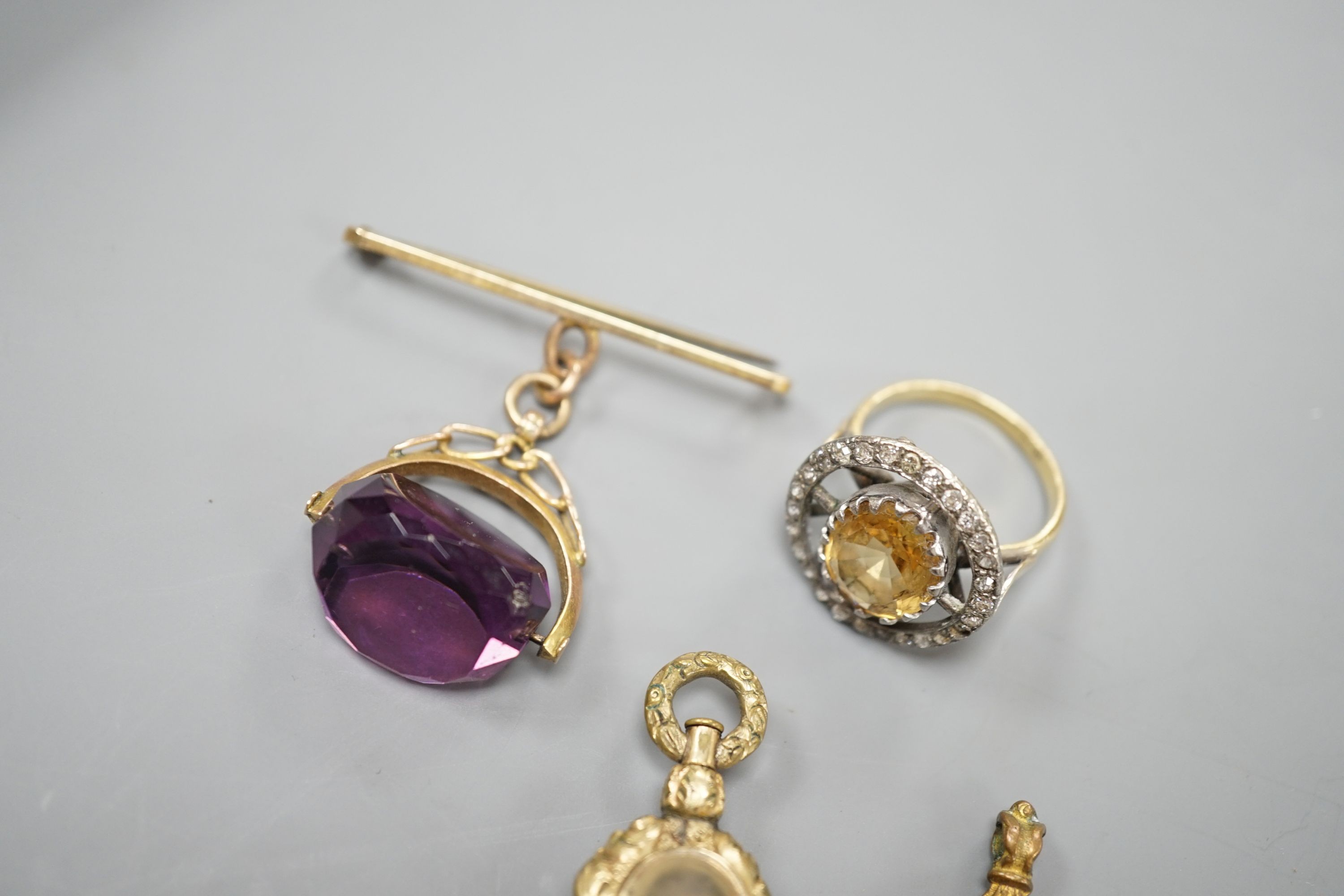 An 18ct, oval cut citrine and round cut diamond set circular cluster dress ring, size R/S, gross 7.1 grams, together with a gem set watch key and two fobs including 9ct brooch suspension.